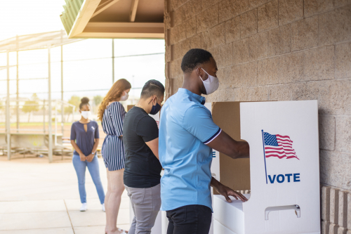 three voters at voting booth with masks on